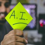 A man holding a post-it with AI written on it