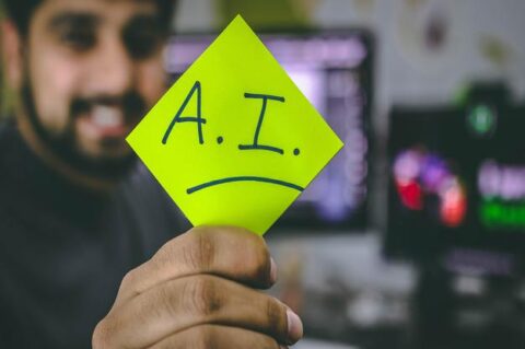 A man holding a post-it with AI written on it